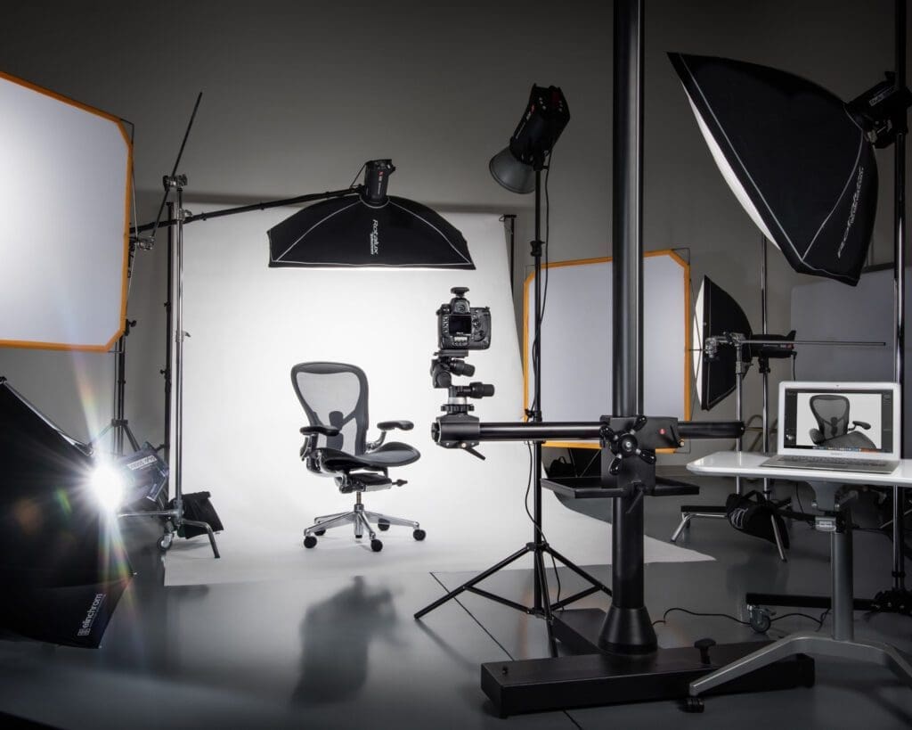 Product photography studio with a wide variety of lighting equipment and a camera arranged around a photographic subject