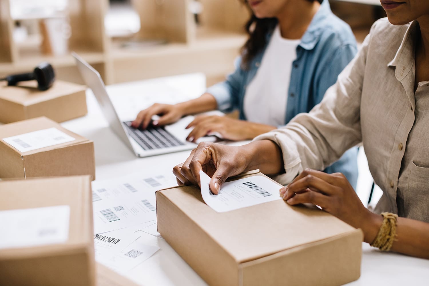 Women applying shipping labels to boxes, readying products for return shipment.